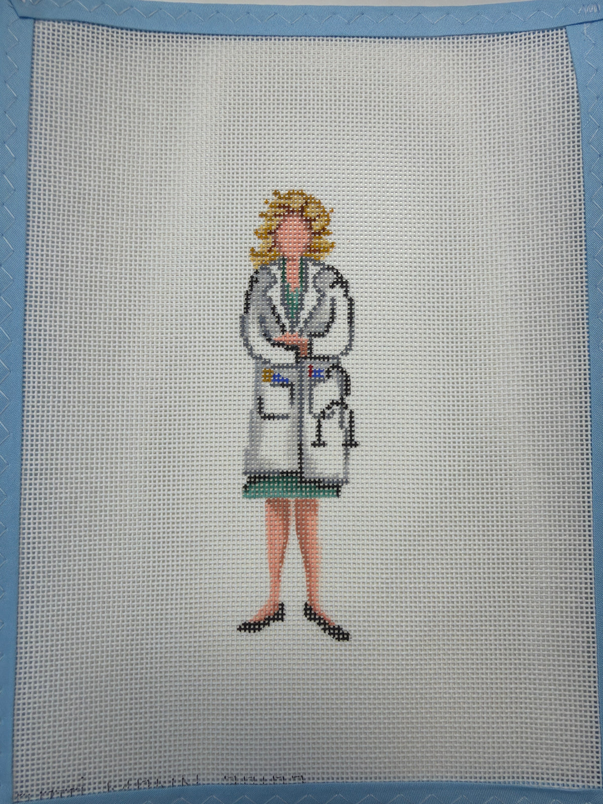 Embroidered doctor figure on textured fabric: hat, lab coat, boots, stethoscope