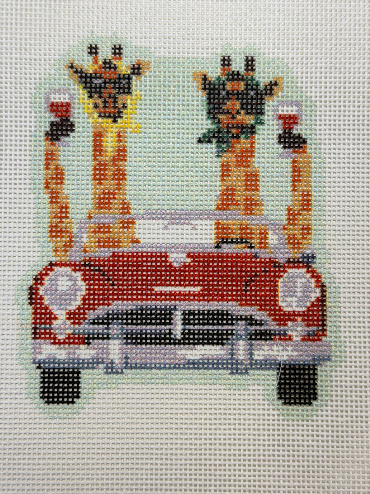 Beaded giraffe artwork with red vehicle and two giraffe figures
