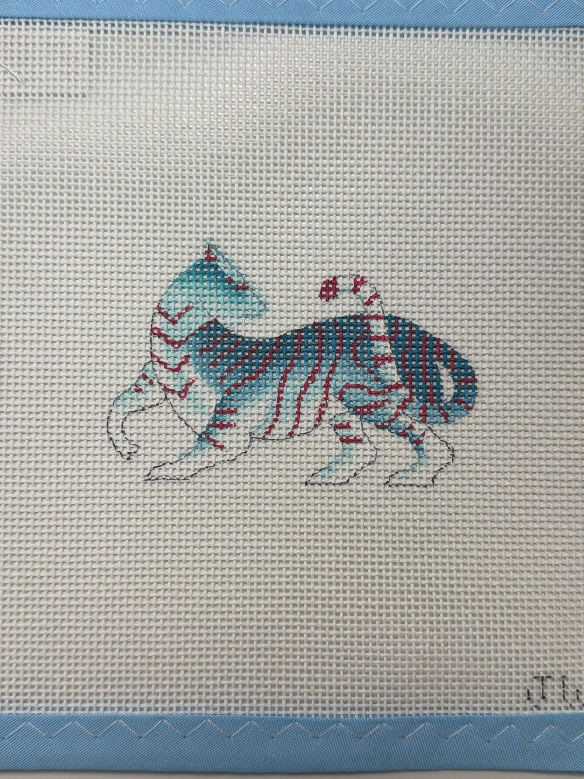 Embroidered wild cat patch on light fabric with blue border