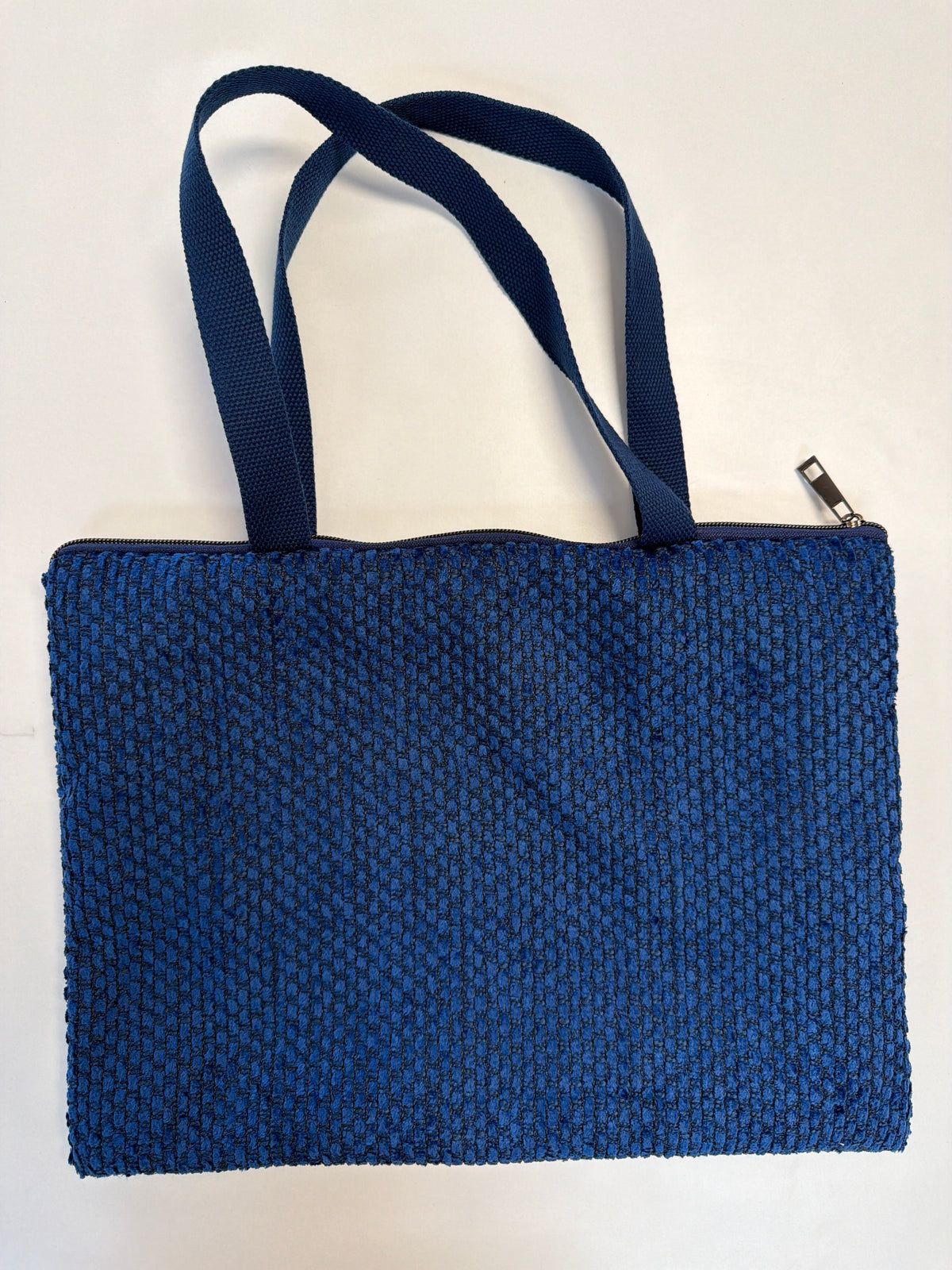 Navy zip-top tote bag with navy web handles and woven texture, rectangular shape