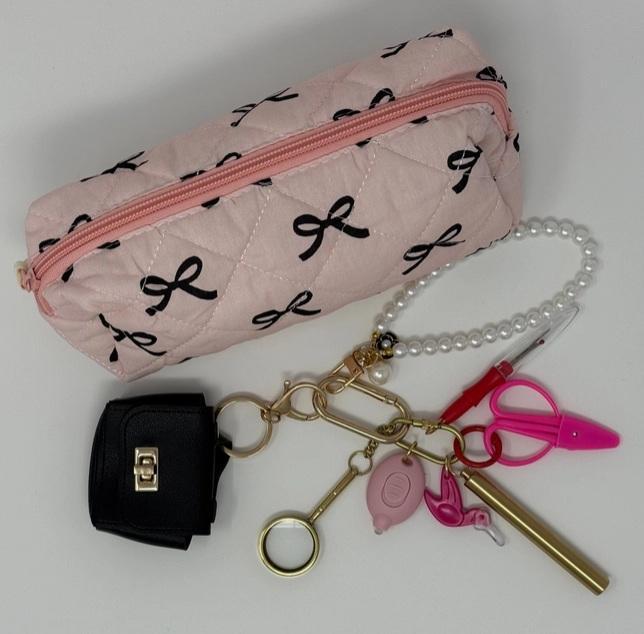 Pearl-bead tool lanyard with brass clips and pink sewing tools beside a bow-print case