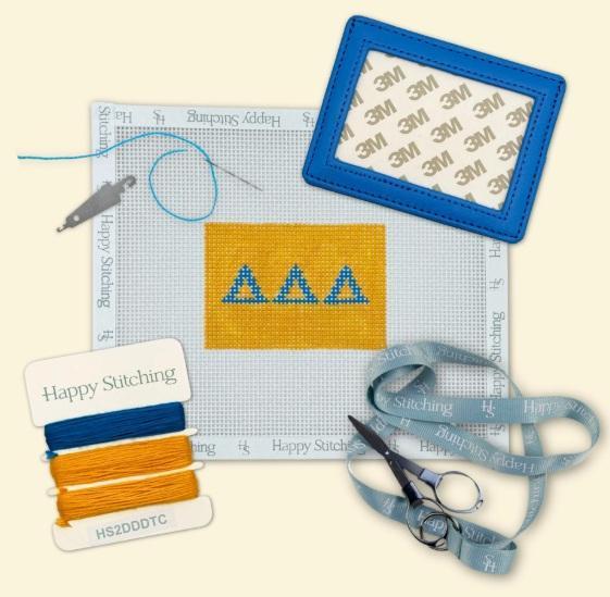 Needlepoint card wallet kit with yellow stitched panel, blue frame, thread and scissors