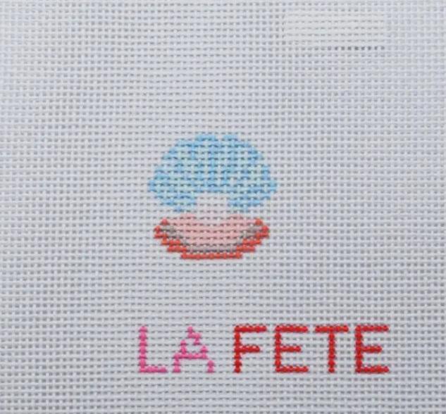 Embroidered oyster shell with pearl motif and “LA FETIE” lettering