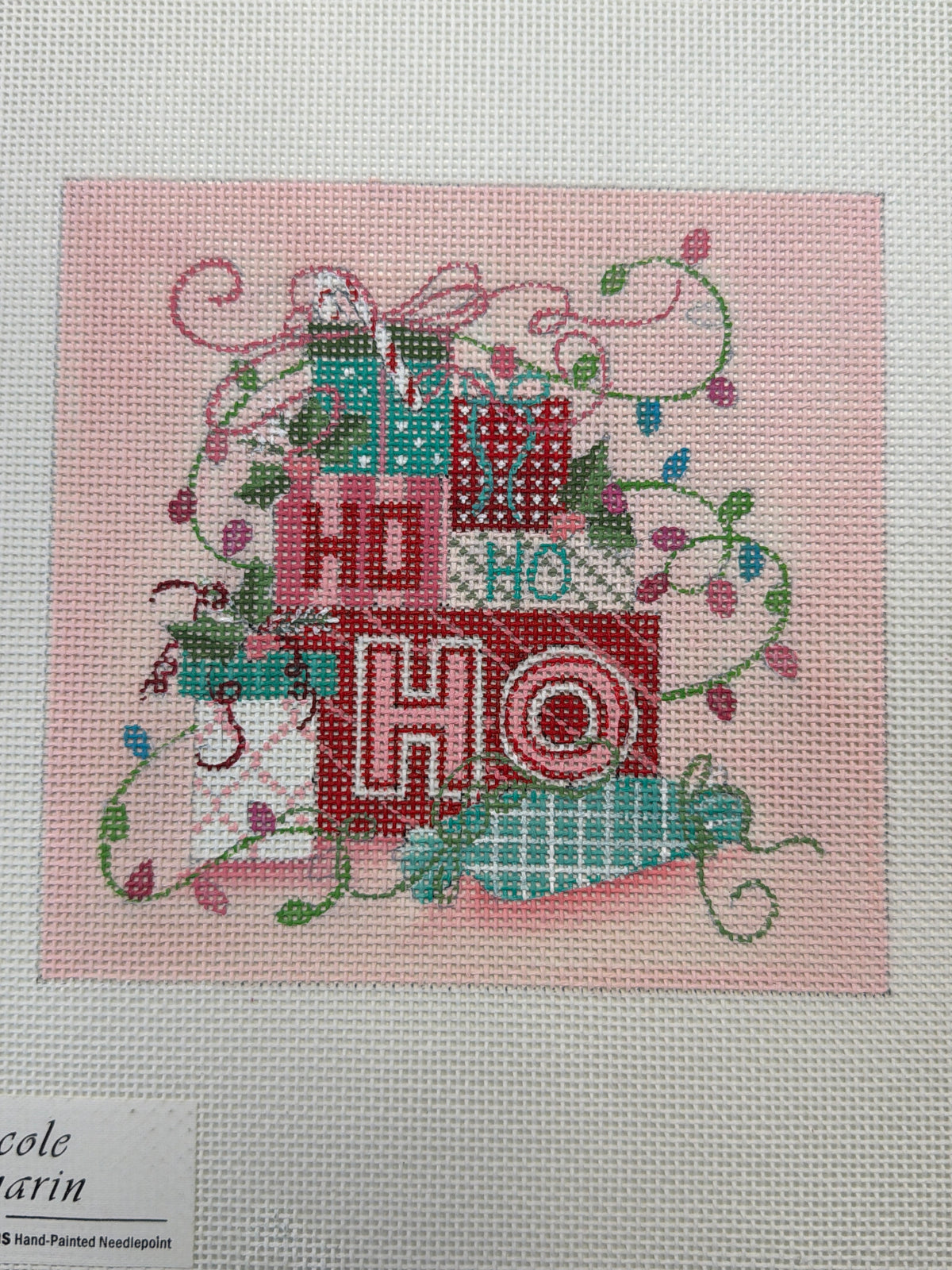 Christmas needlepoint wall art with wrapped gift, ornaments, and decorative ribbon stitch