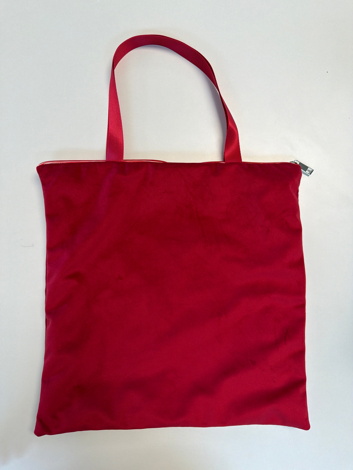 Red zip-top tote bag with red handles, flat square tote style
