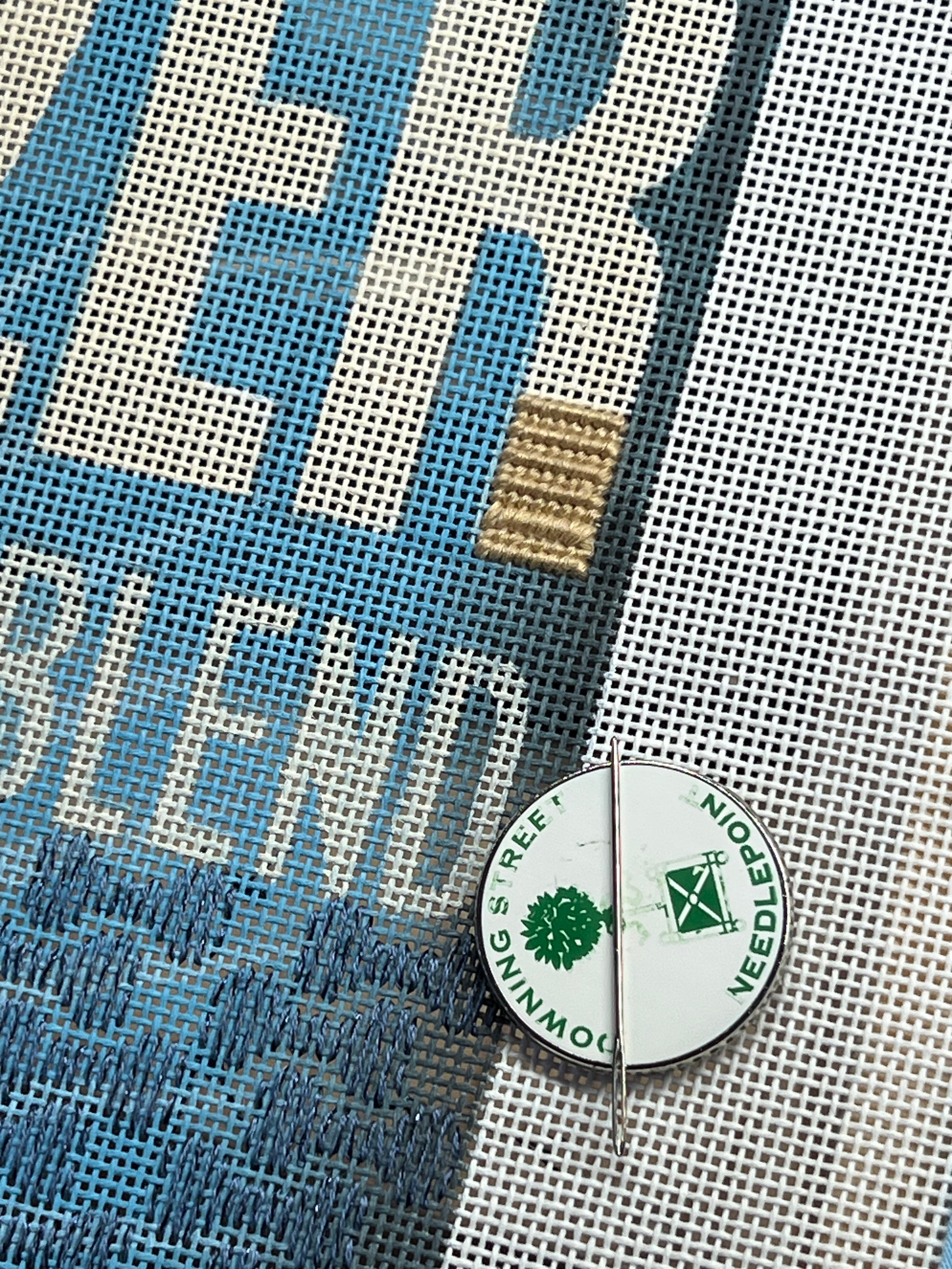 Blue and white mesh needlepoint canvas with two round enamel pins