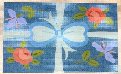 Needlepoint insert with a white bow, pink flowers, and green leaves on a blue ground