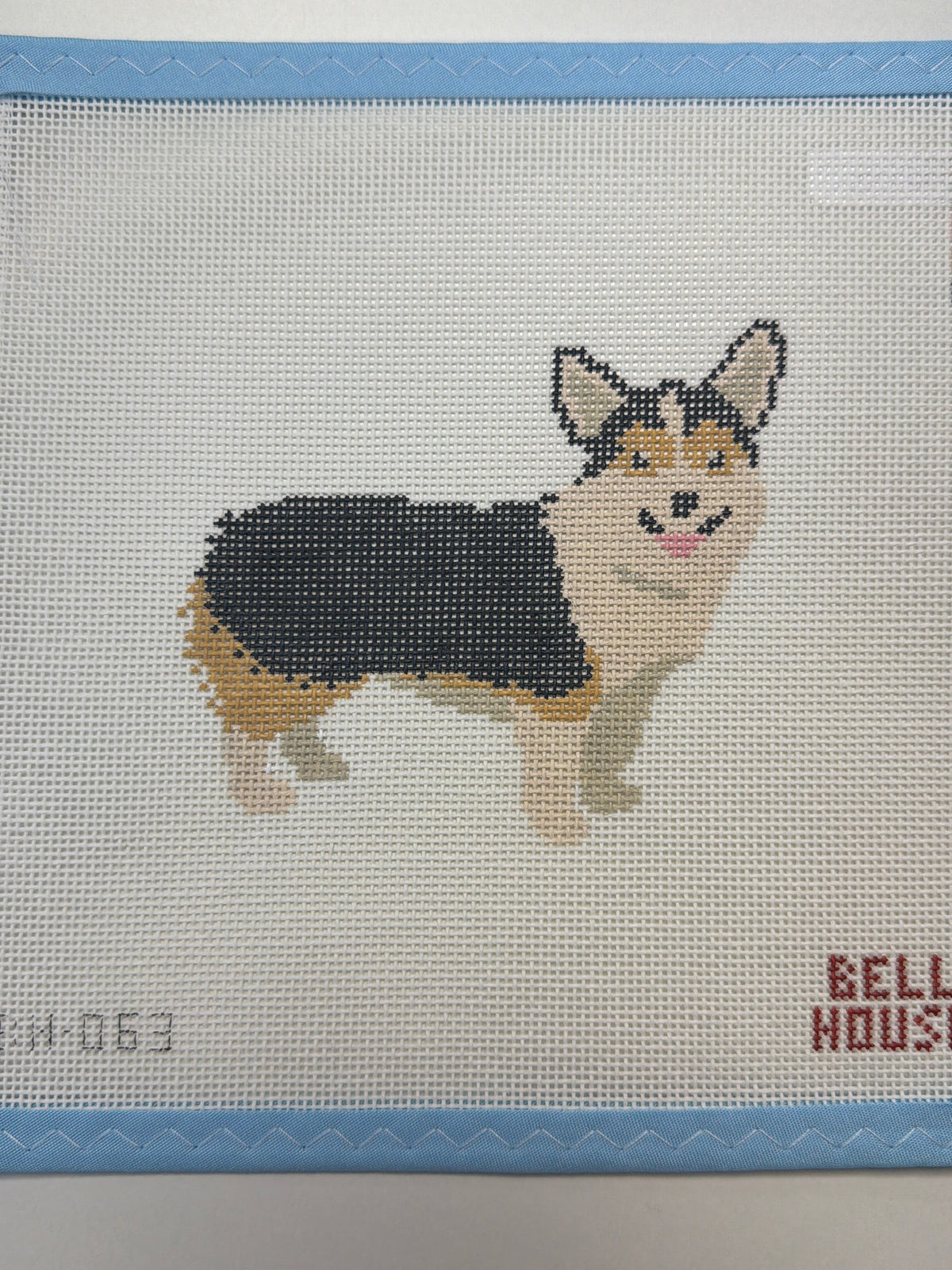 Embroidered black-and-tan dog standing with head turned