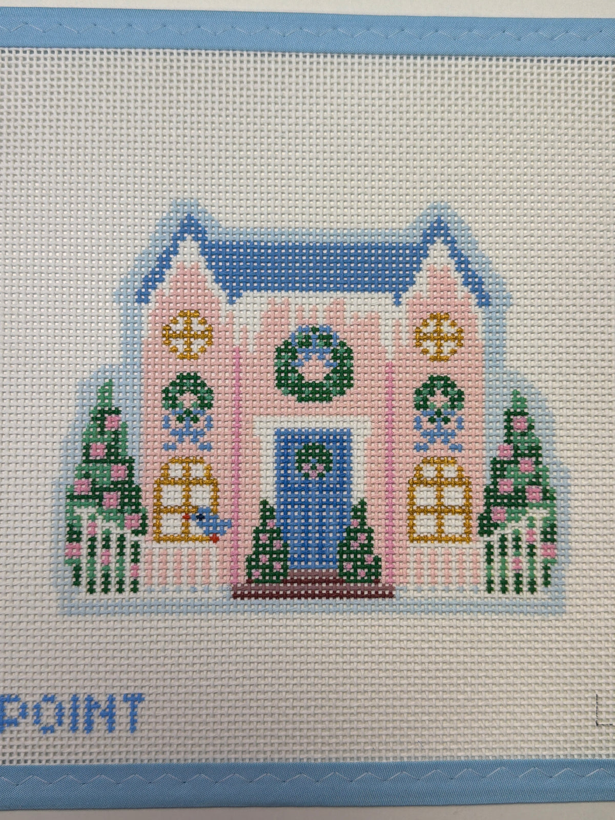 Embroidered pink house design on light fabric with blue door and green trees