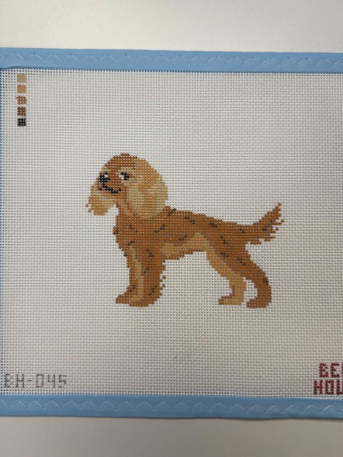 Embroidered reddish-brown dog sitting in side view with tail raised