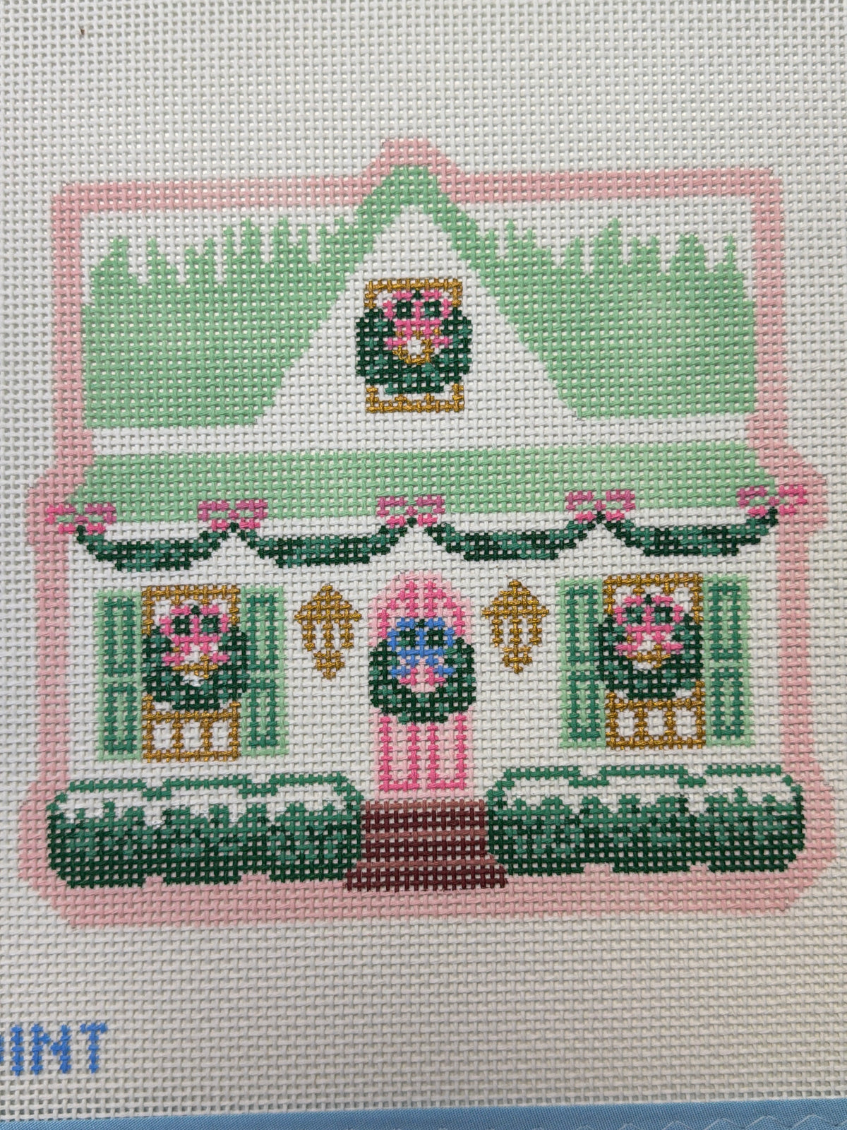 Needlepoint canvas with green house and floral border motifs