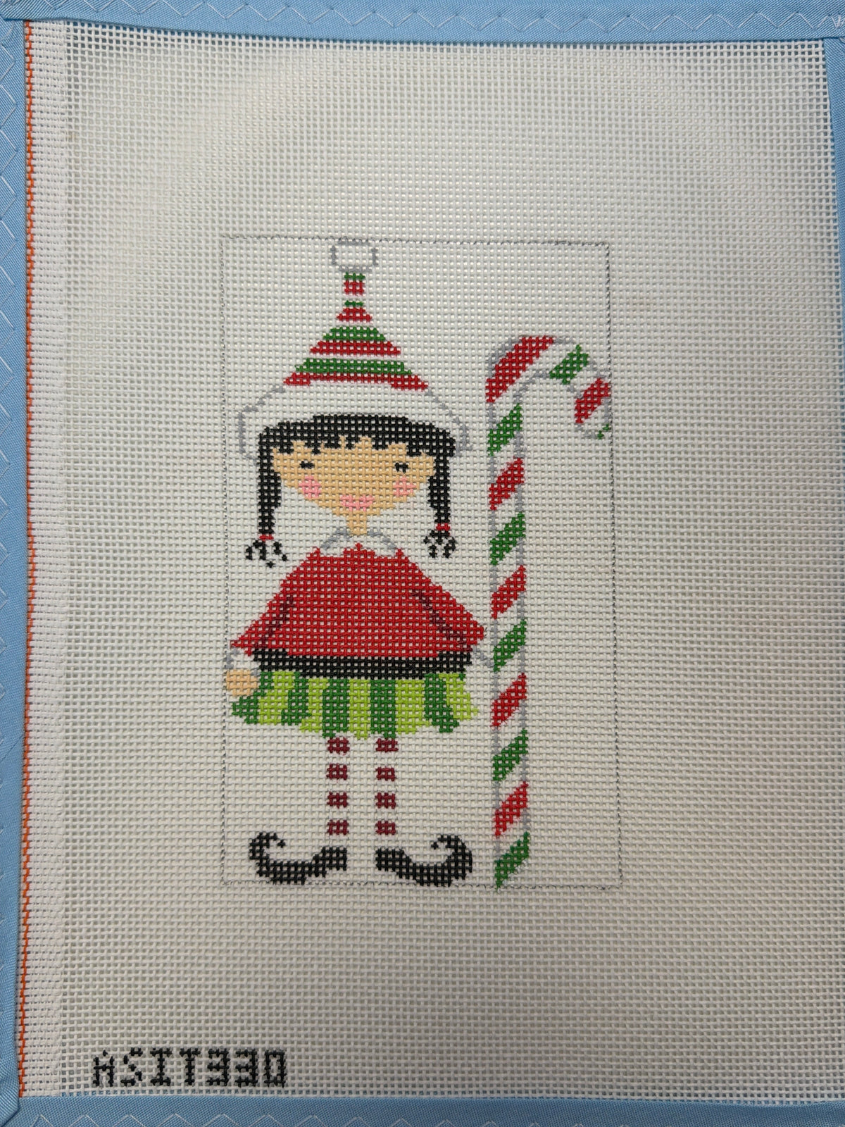 Embroidered elf holding a striped candy cane, colorful holiday motif on fabric panel
