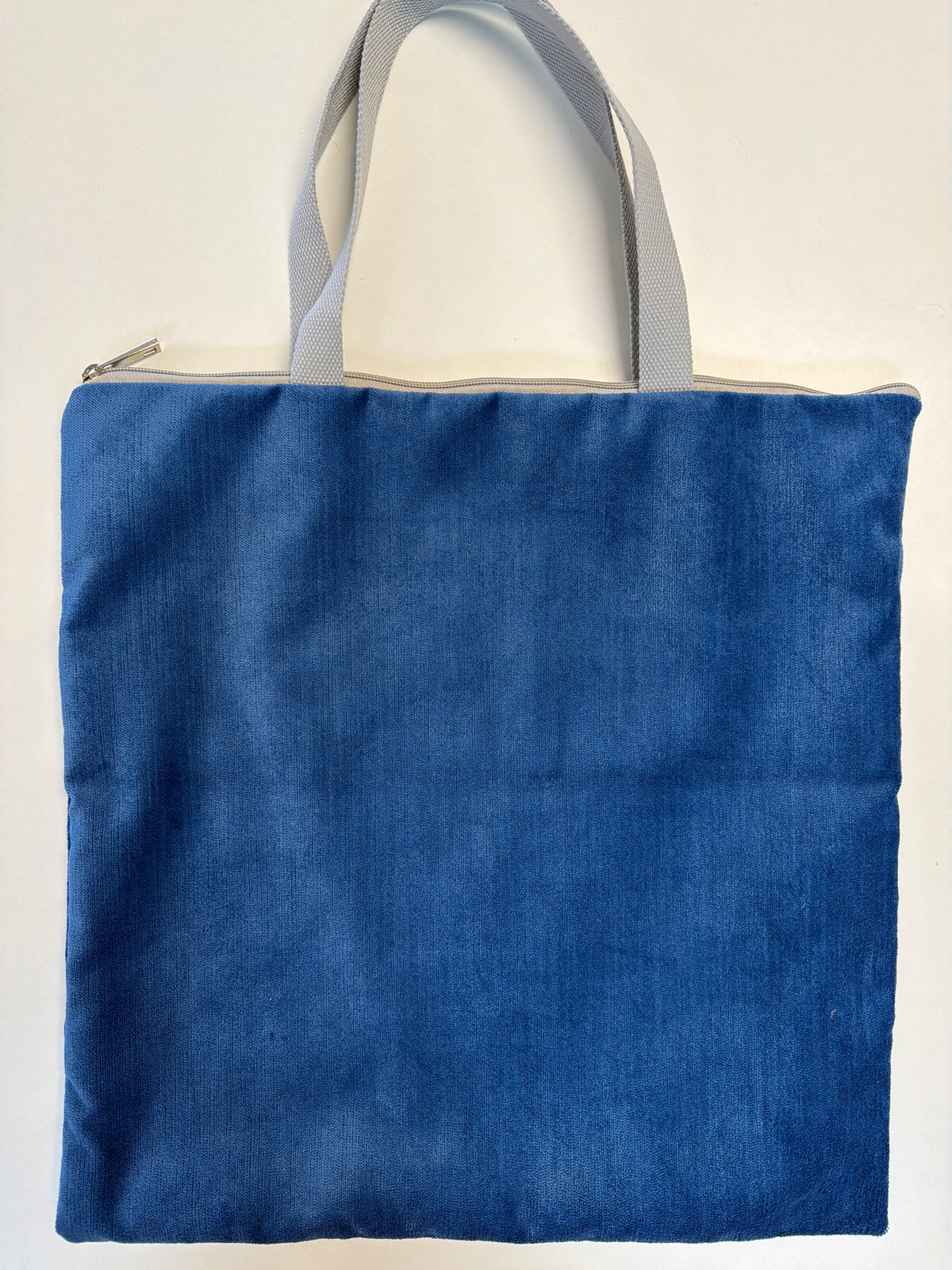 Blue zip-top tote bag with light gray handles and flat rectangular shape