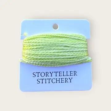 Hand-dyed embroidery thread spool in light lime green on a card backing.