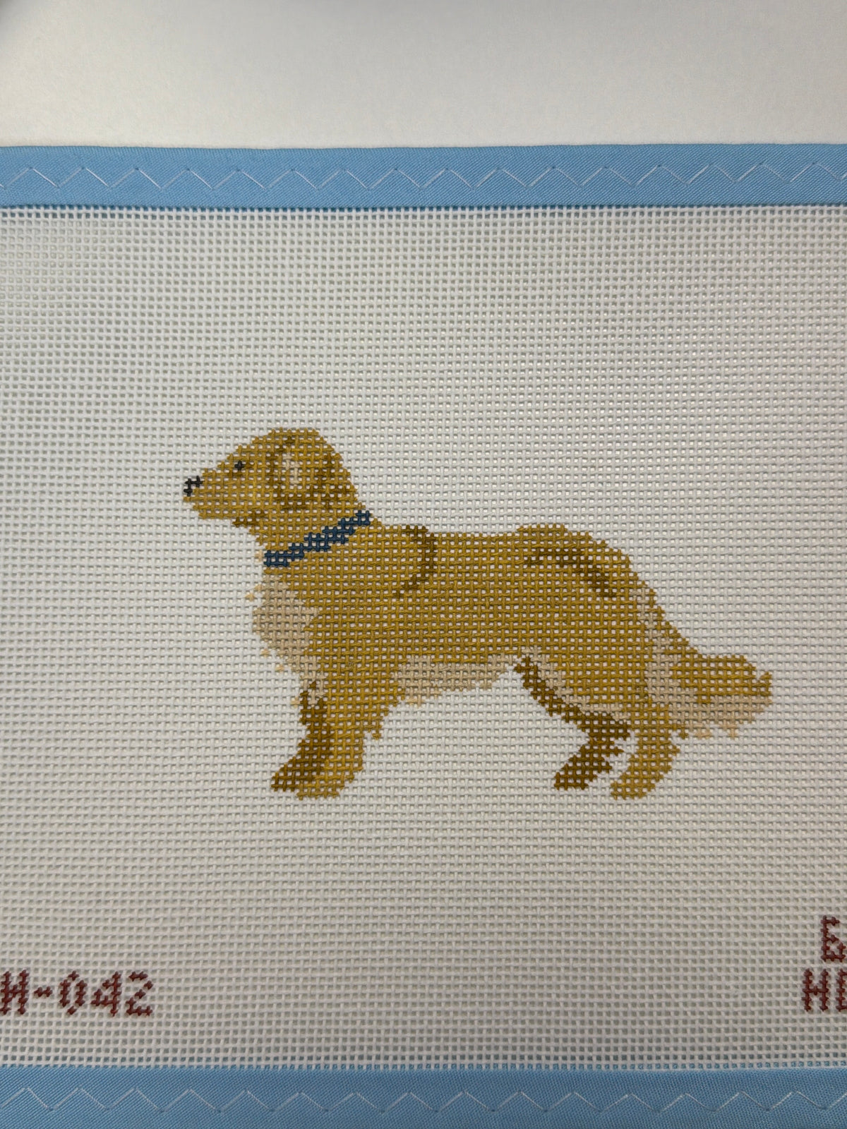 Embroidered golden-brown dog standing in profile with collar
