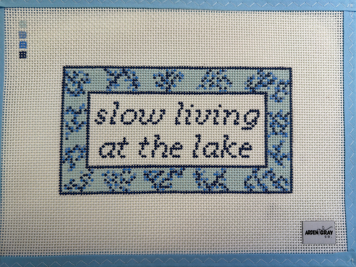 Blue-bordered textile wall hanging with black Arabic-style lettering