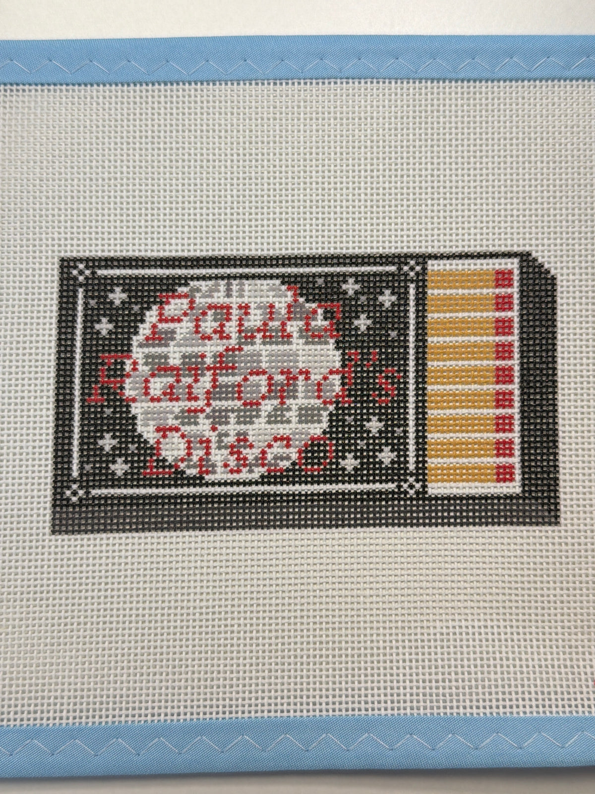 Decorative matchbox-style patch with starry text panel and striped matches side