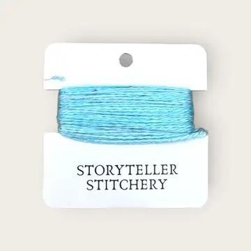 Hand-dyed embroidery thread on card, light aqua-blue skein on white backing