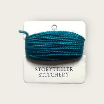 Hand-dyed embroidery thread spool, dark teal on a card backing