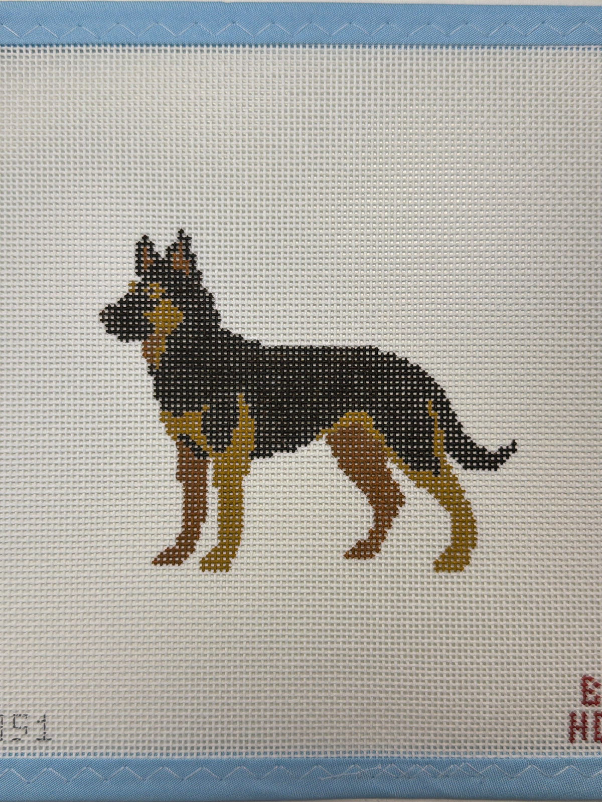 Embroidered dark dog with tan legs standing in side profile