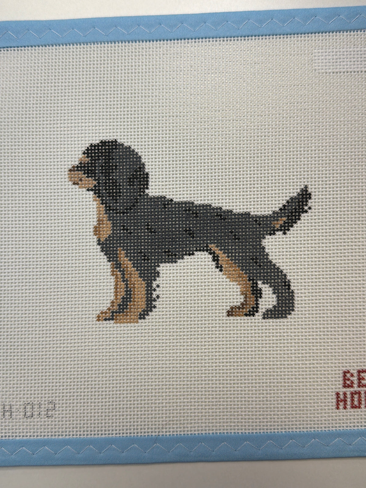 Embroidered black-and-tan dog standing with head turned in profile