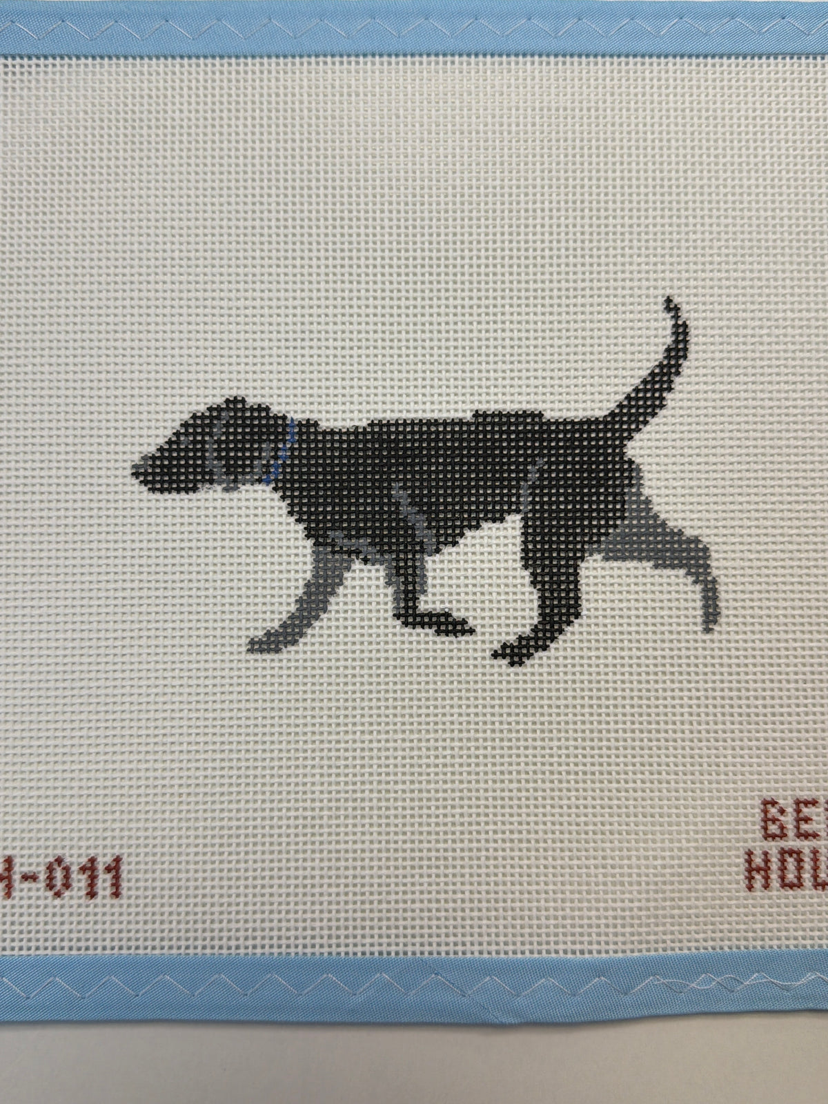 Embroidered black dog with white chest standing in side view