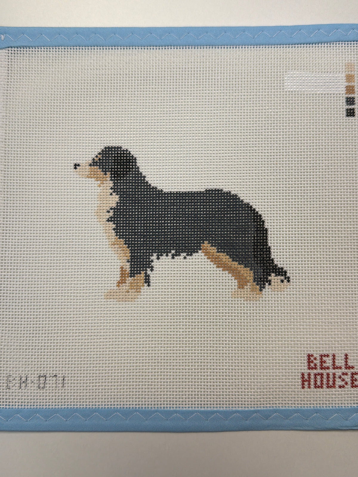 Embroidered black dog standing with tan paws and tail raised