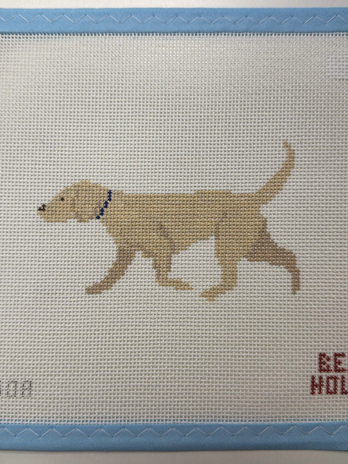 Embroidered light tan dog standing in profile with blue collar
