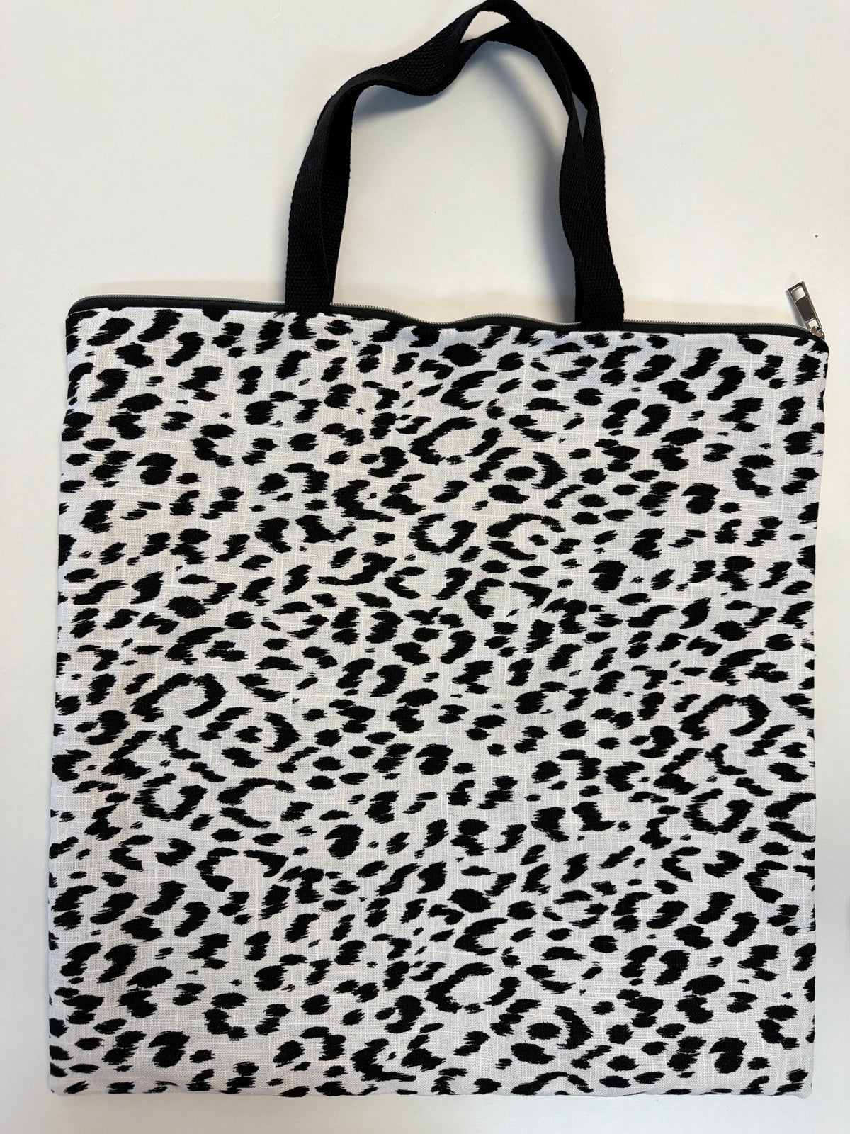 White zip-top tote bag with black leopard-print front and black top handles
