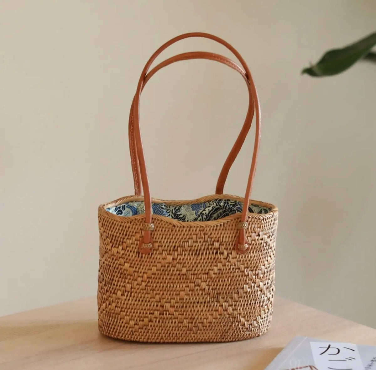 Rattan tote bag with tan woven basket, leather-look handles, blue patterned lining