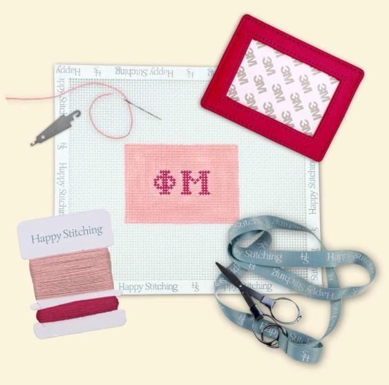 Needlepoint card wallet kit with pink stitched panel, red frame, thread and scissors