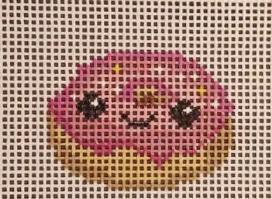 Pink and yellow donut needlepoint on a square grid canvas