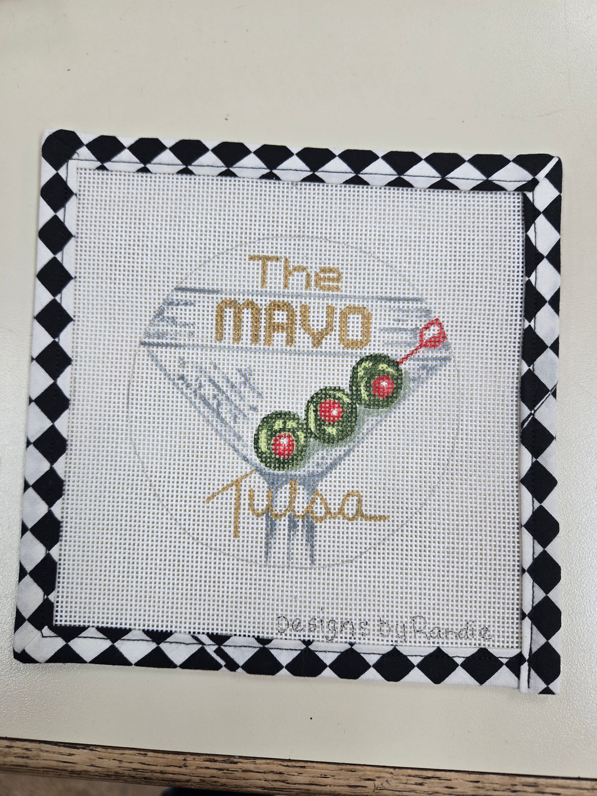 The Mayo martini needlepoint square with a cocktail glass and olive garnish