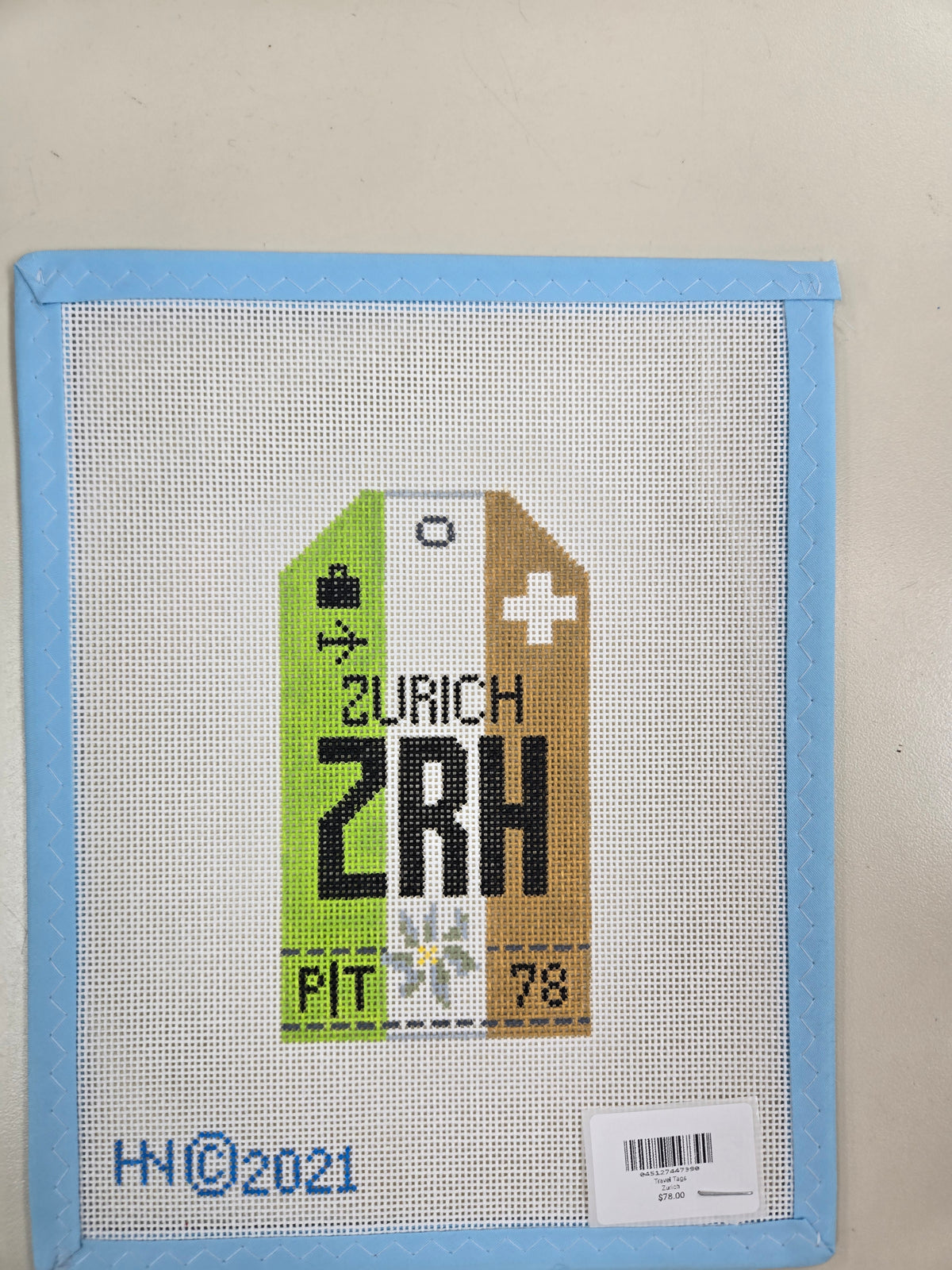 Cross-stitch Zurich travel tag with green, white, and brown panels and ZRH lettering