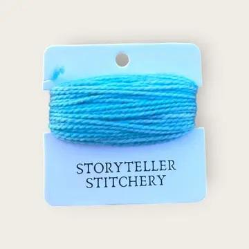Hand-dyed embroidery thread spool, light blue on a card backing
