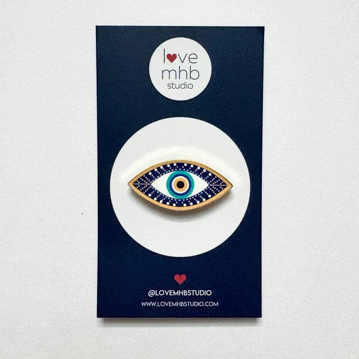 Evil eye leather charm with blue and gold enamel-style eye on tan leather backing