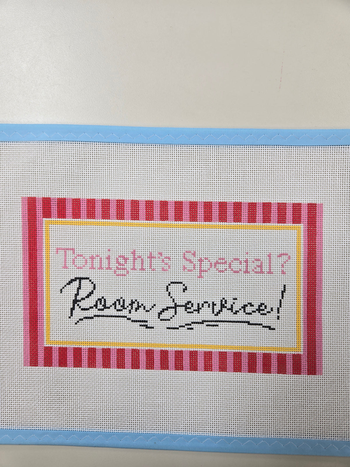 Embroidered “Room Service” patch with red plaid border on light gray fabric