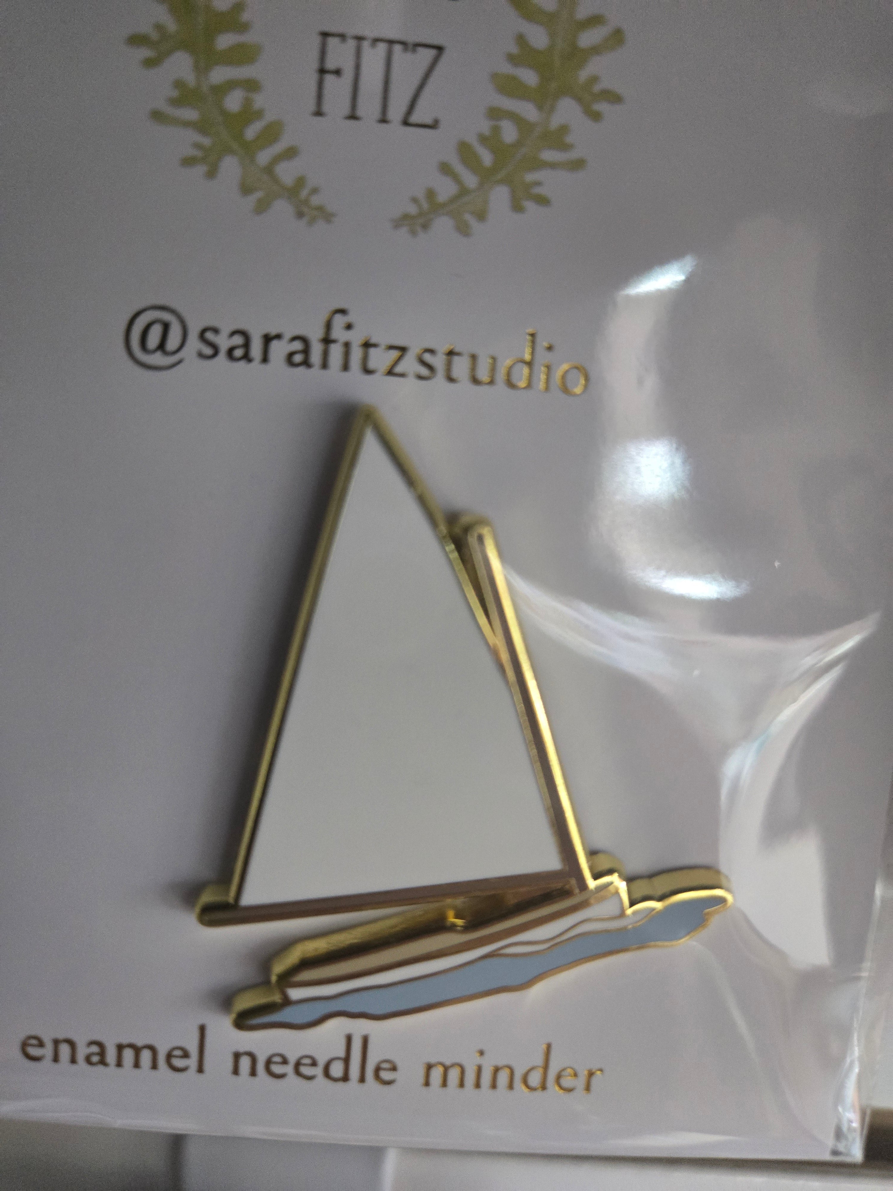 Gold sailboat enamel needle minder with white sail, small clasp on back