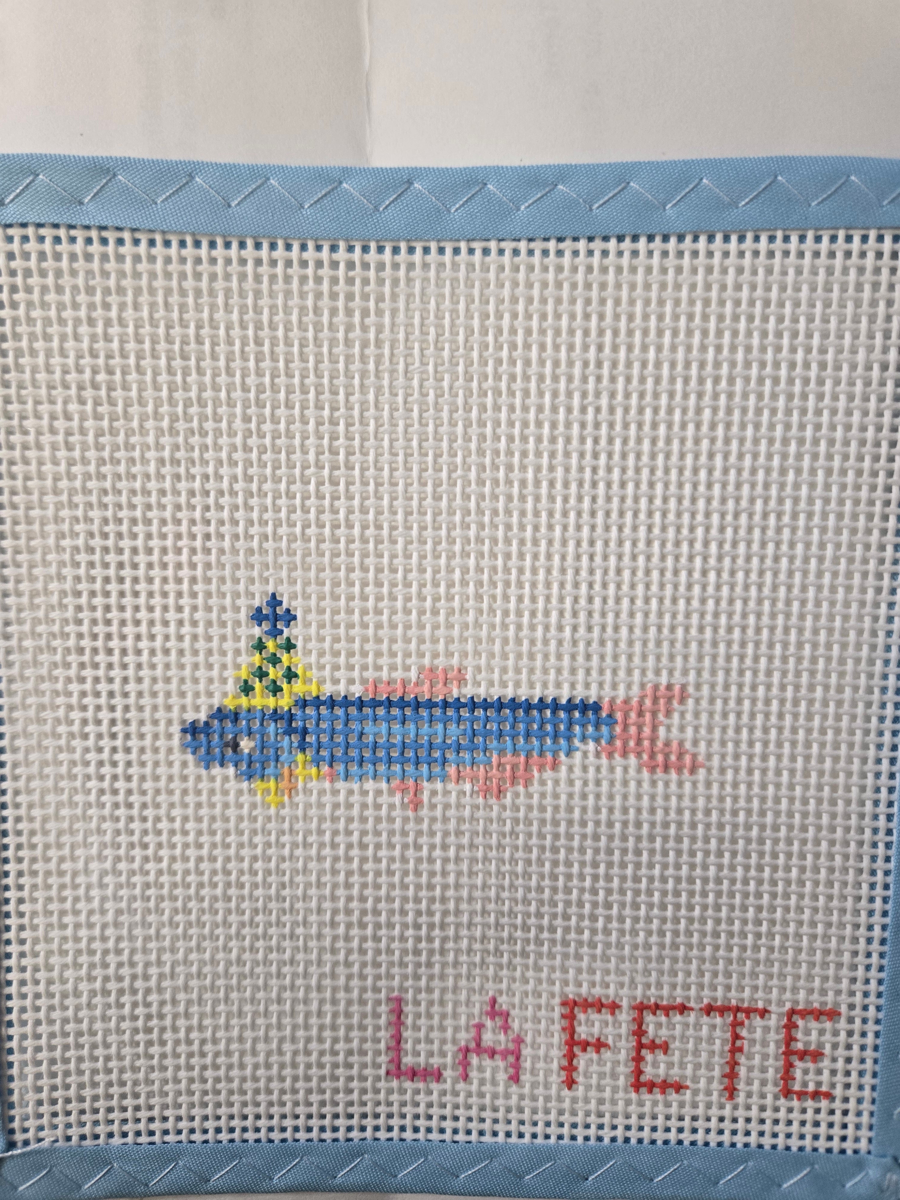 Embroidered sardine motif on beige fabric with multicolor fish and red text