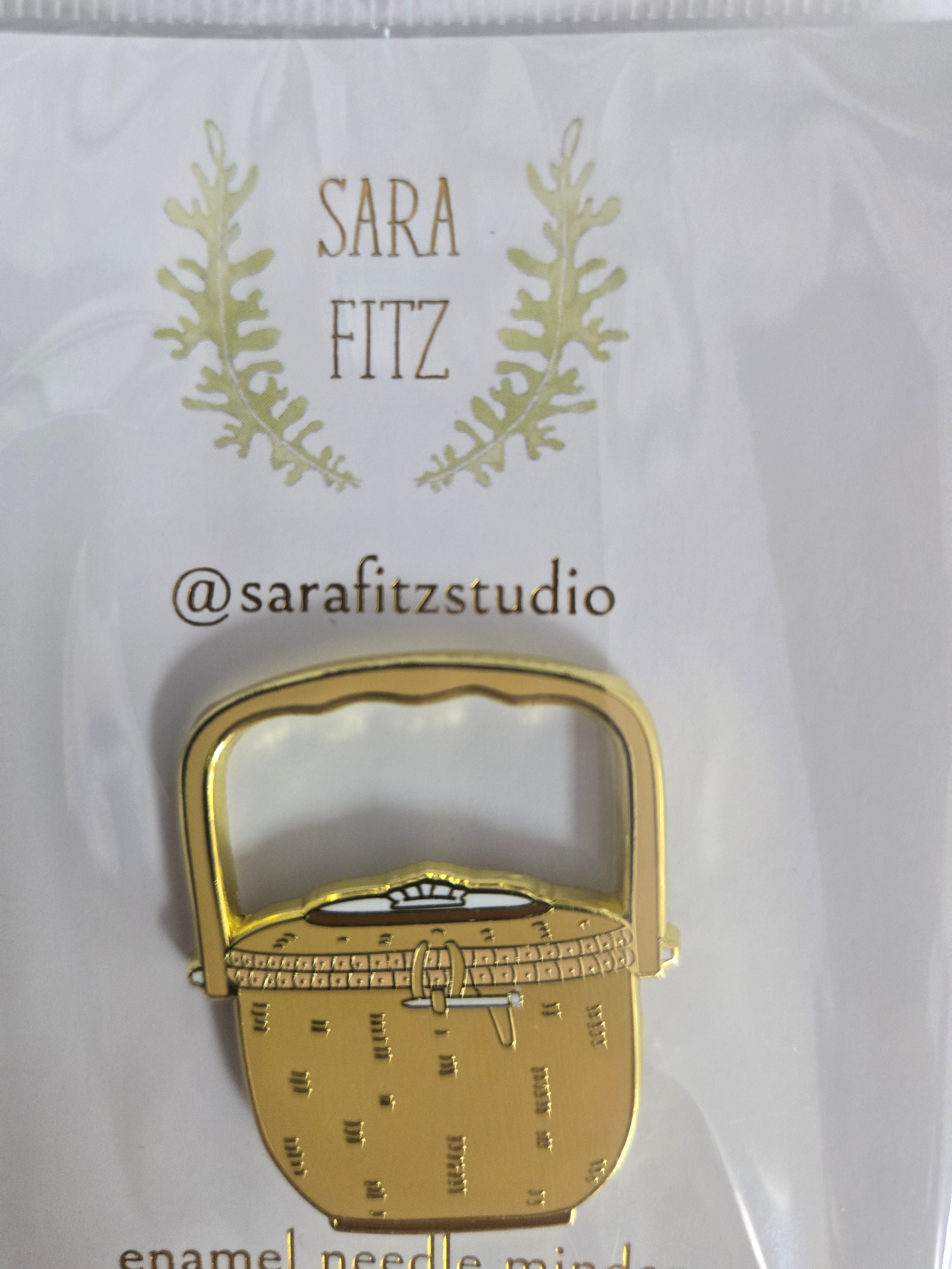 Enamel needle minder shaped like a small lock, gold-toned with house detail