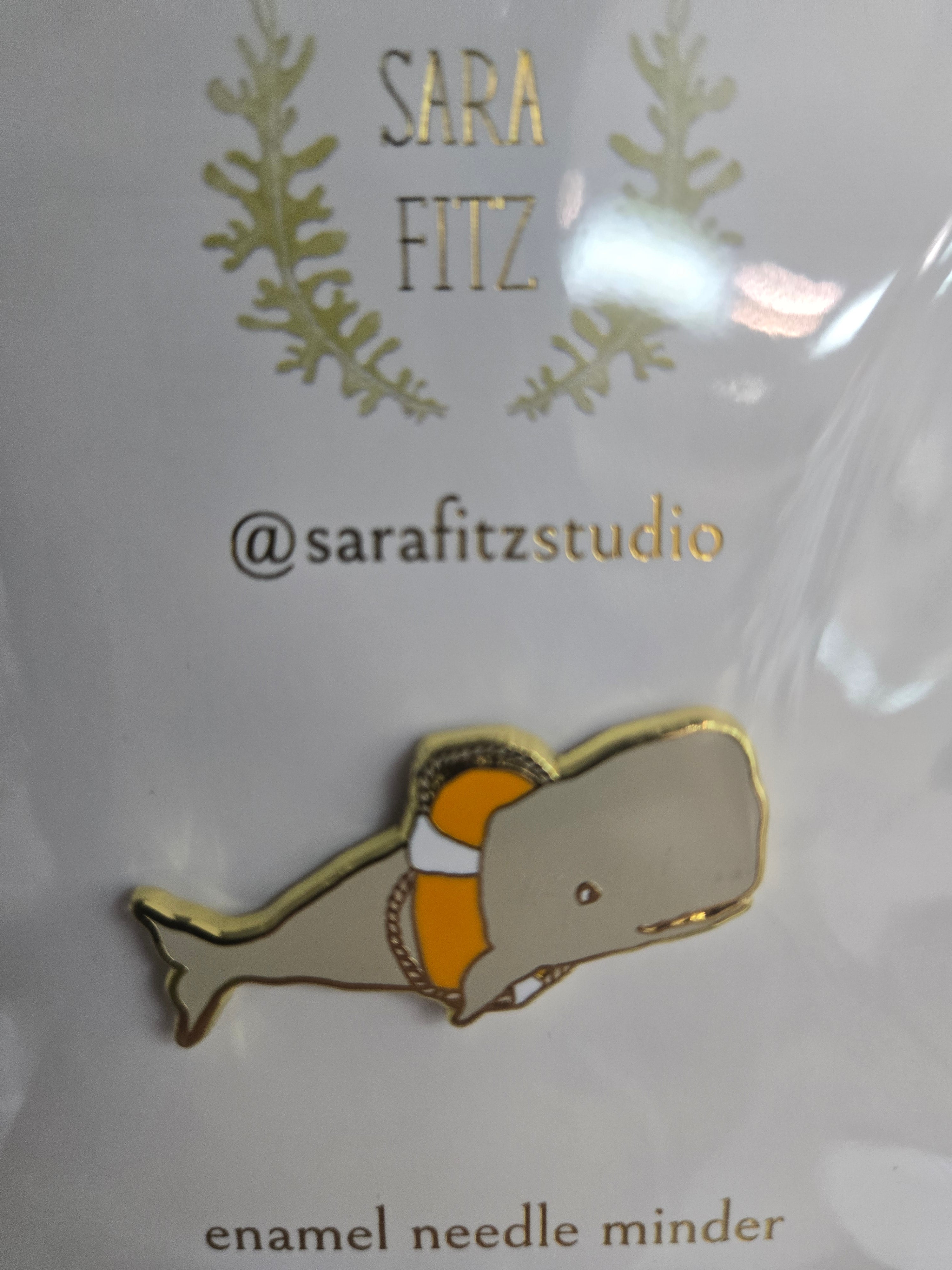 Enamel whale needle minder pin with orange belly and gold outline