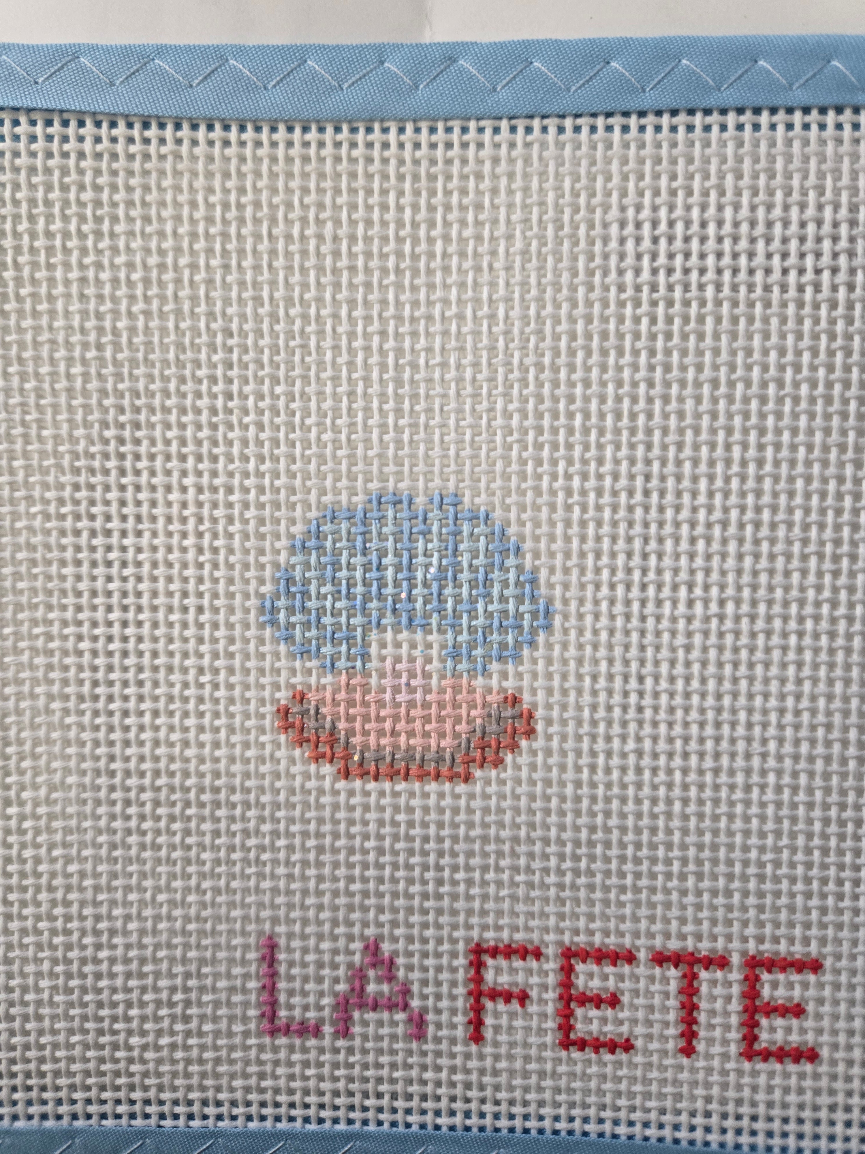 Embroidered glitter shell motif with pearl, with red “LA FETE” text on fabric
