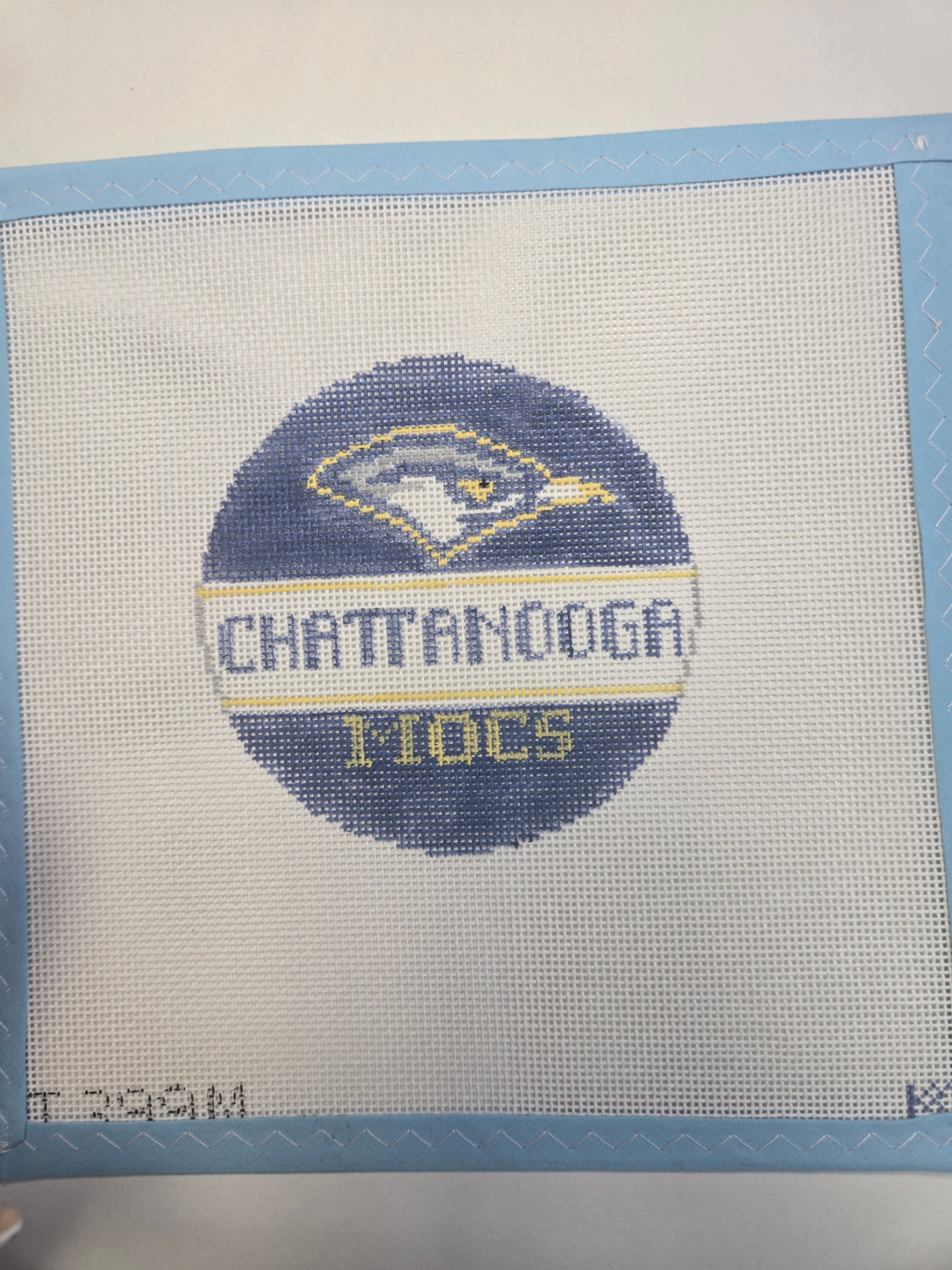 Embroidered circular Chattanooga Mocs logo with blue border on light fabric